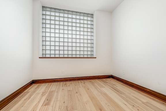 A room with a window and wooden flooring.