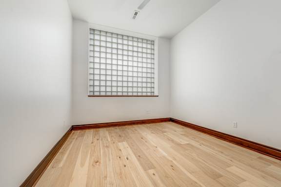 A room with a window and wooden flooring.