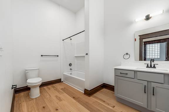 A white toilet sits in a bathroom with a white tub and sink.