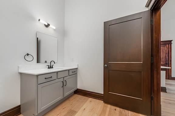 A bathroom with a sink, mirror, and wooden door.