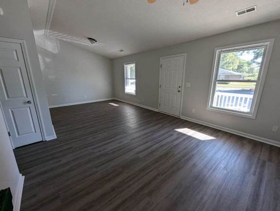 an empty living room with wooden floors and a window