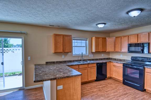 A kitchen with wooden cabinets and a granite countertop.