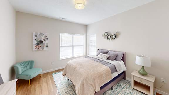 A bedroom with a bed, chair, and lamp.