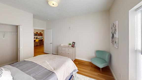 A bedroom with a bed, dresser, and chair.