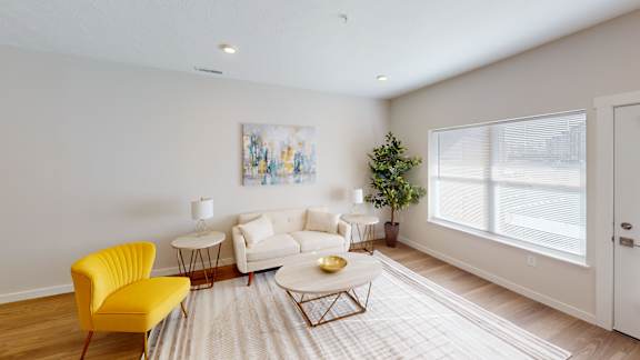 A living room with a yellow chair and a white couch.