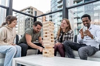 Four people playing a game of Jenga in an office setting. at Citizen on Jasper, Edmonton, AB