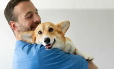 Man is holding a corgi dog in his arms at Citizen on Jasper, Alberta