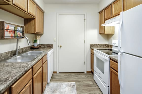 A kitchen with a white refrigerator, sink, and oven at The Pointe in La Vista, NE