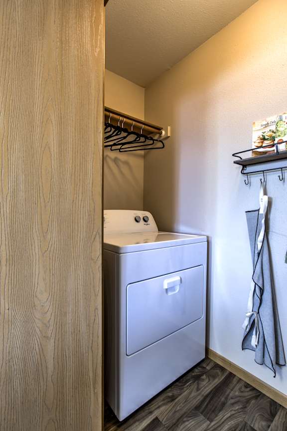 A white washing machine is in a small laundry room. at Tranquility Pointe, Omaha, NE