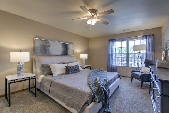 A bedroom with a large bed and a ceiling fan. at Tranquility Pointe, Omaha