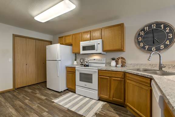 A kitchen with a white refrigerator, wooden cabinets at Tranquility Pointe, Omaha