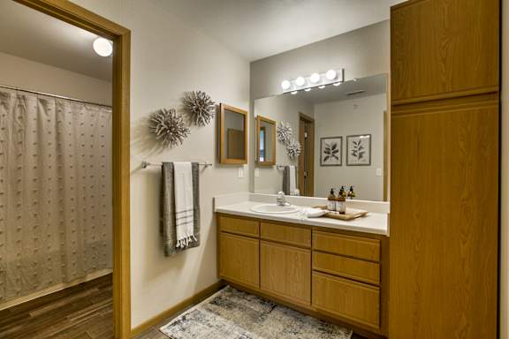 A bathroom with a wooden vanity and a mirror above it. at Tranquility Pointe, Omaha, NE
