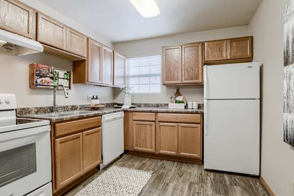 A kitchen with wooden cabinets and a white refrigerator. at The Pointe, Nebraska, 68128