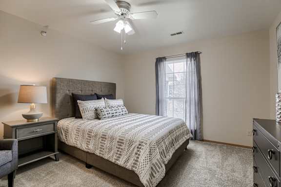 A bedroom with a large bed and a ceiling fan. at The Pointe, Nebraska, 68128