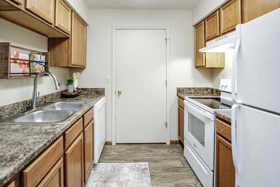 A kitchen with a white refrigerator, sink, and cabinets. at The Pointe, Nebraska, 68128