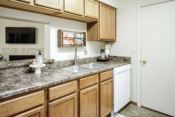 A kitchen with wooden cabinets and a granite countertop. at The Pointe, LaVista, 68128