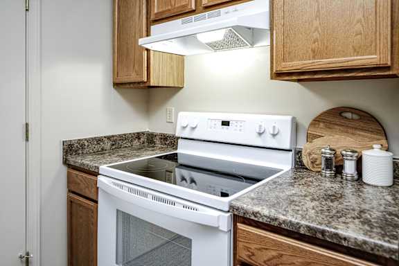 A white oven with a stove top sits on a granite countertop. at The Pointe, Nebraska, 68128