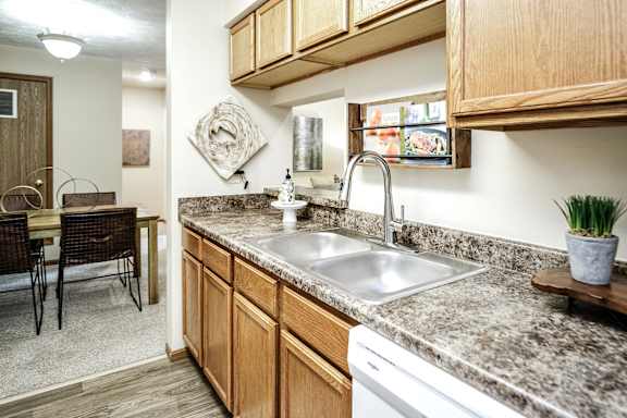 A kitchen with a granite countertop and wooden cabinets. at The Pointe, LaVista, NE, 68128