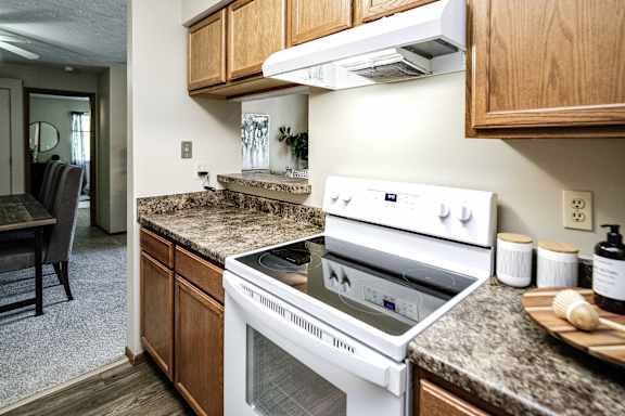 A white stove top oven with a silver handle is on a granite counter. at The Pointe, LaVista, NE, 68128