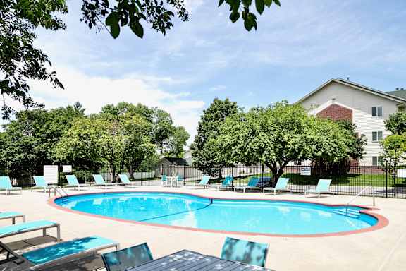 A pool surrounded by trees and chairs. at The Pointe, LaVista, Nebraska