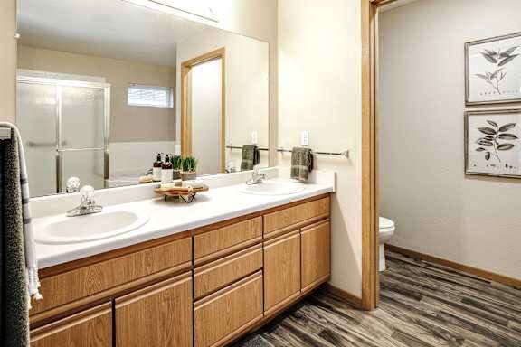 A bathroom with a wooden vanity and two sinks. at Tranquility Pointe, Nebraska, 68164