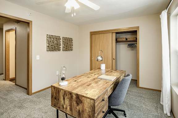 A room with a wooden desk and a chair. at Tranquility Pointe, Omaha