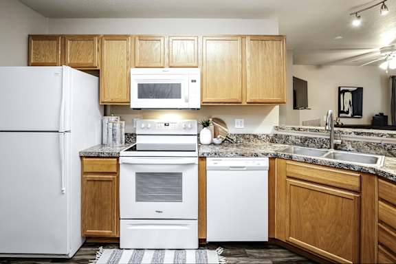 A kitchen with white appliances and wooden cabinets. at Tranquility Pointe, Nebraska