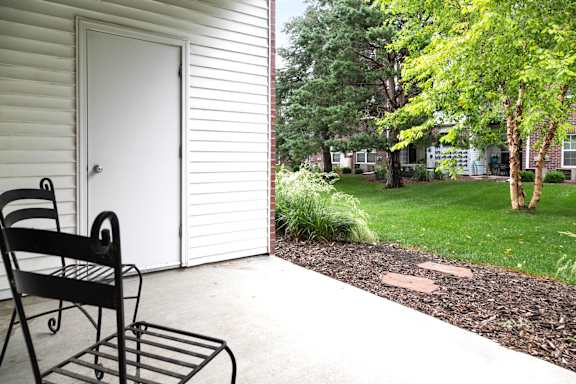 A black chair sits on a patio next to a white door. at Tranquility Pointe, Omaha