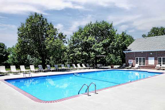 swimming pool surrounded by trees and lounge chairs at Tranquility Pointe apartments in Omaha, NE