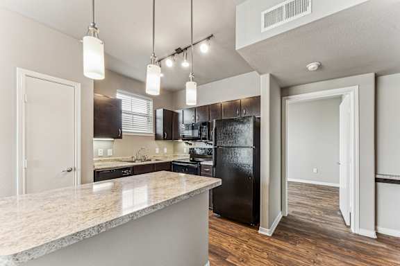 Modern kitchen with dark cabinetry and granite island at Gateway Cedars Apartments, Texas, 75126