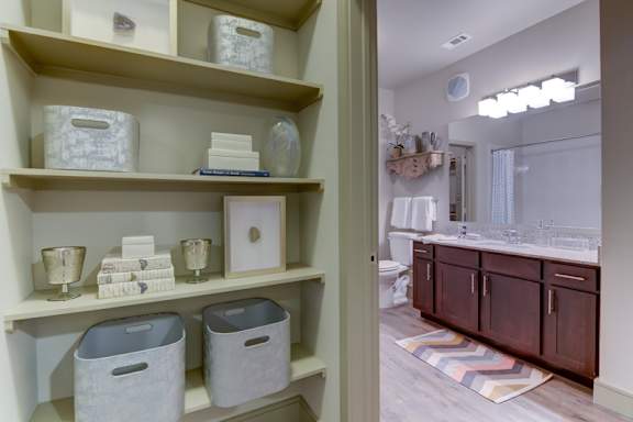 A bathroom with a white shelf containing various items.