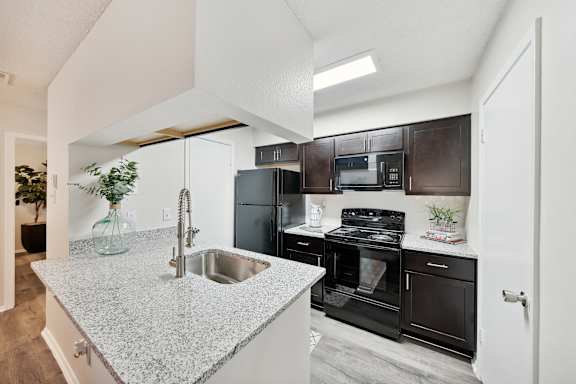 A kitchen with a granite countertop and black appliances.