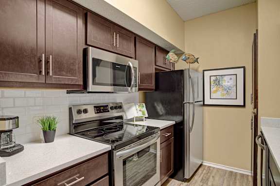 Galley kitchen with dark cabinetry and stainless appliances at Arbors at Wolf Pen Creek Apartments, Texas, 77840