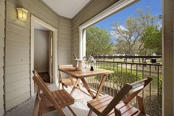A wooden table and chairs are on a balcony.