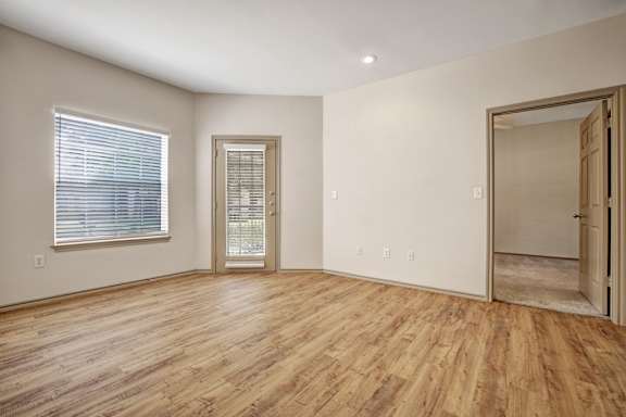 A room with wooden flooring and a door on the right.