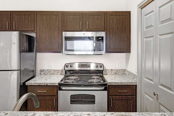 A kitchen with a stove, microwave, and refrigerator.