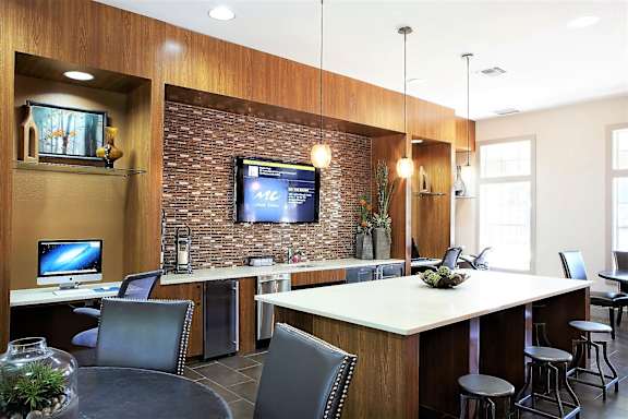 A modern kitchen with a bar area and a television mounted on the wall.