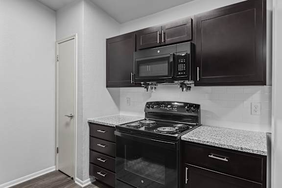 A kitchen with black cabinets and a black stove top oven.