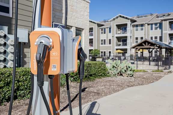 A charging station for electric vehicles is shown in front of apartment buildings.