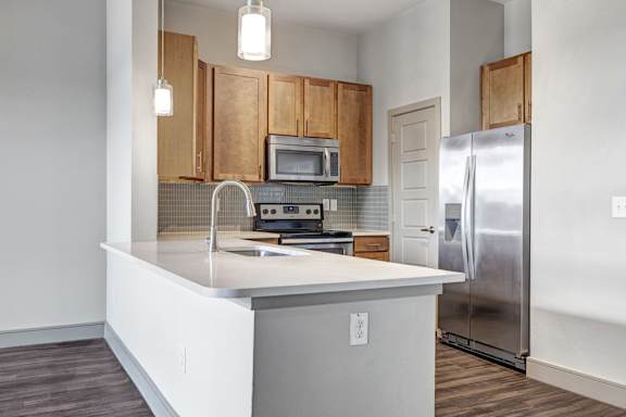 A kitchen with a white counter top and wooden cabinets.