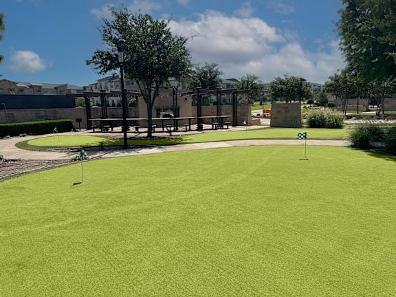 Putting green with seating area and shade structures at Gateway Cedars Apartments, Forney