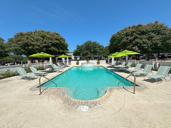 Outdoor pool with turquoise water and lounge chairs at La Calera Apartments, Texas