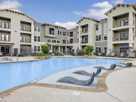 A large swimming pool in front of apartment buildings.