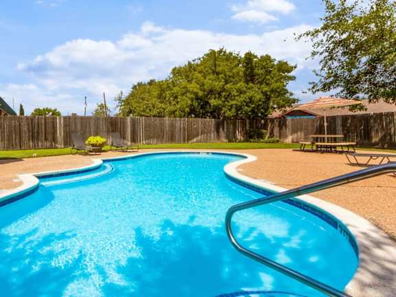 Freeform swimming pool with surrounding patio deck at Quail Crossing Apartments, Grand Prairie