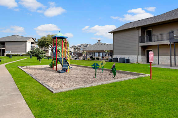 Playground with colorful equipment and spring riders at Riviera Apartments, Waco