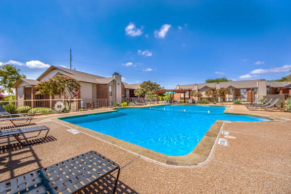 Poolside with lounge chairs and residential backdrop at Valley Creek Apartments, Garland, TX