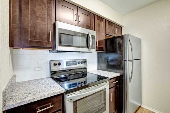 A kitchen with a stove, oven, microwave and refrigerator.