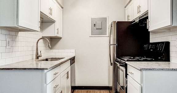 A kitchen with white cabinets and a black refrigerator.