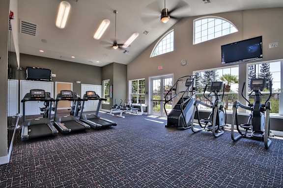 A gym with treadmills, exercise bikes, and a television at Rosemeade Apartments, Roseville, 95661
