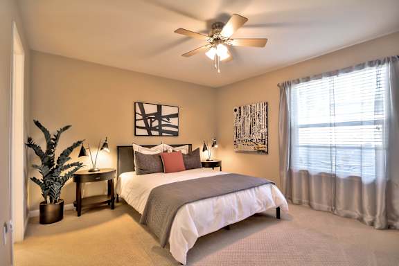 Spacious bedroom with ceiling fan and large window at Rosemeade Apartments, Roseville, California